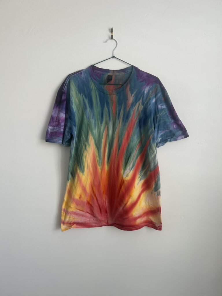 Vibrant sunburst tie-dye shirt with red, yellow, green, and blue flame-like pattern on cotton fabric