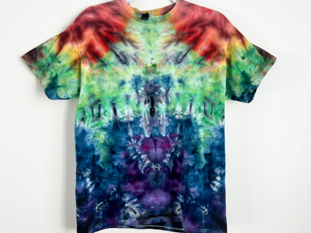 Rainbow galaxy-inspired tie-dye shirt using ice dye technique on cotton fabric with bold, blended colors