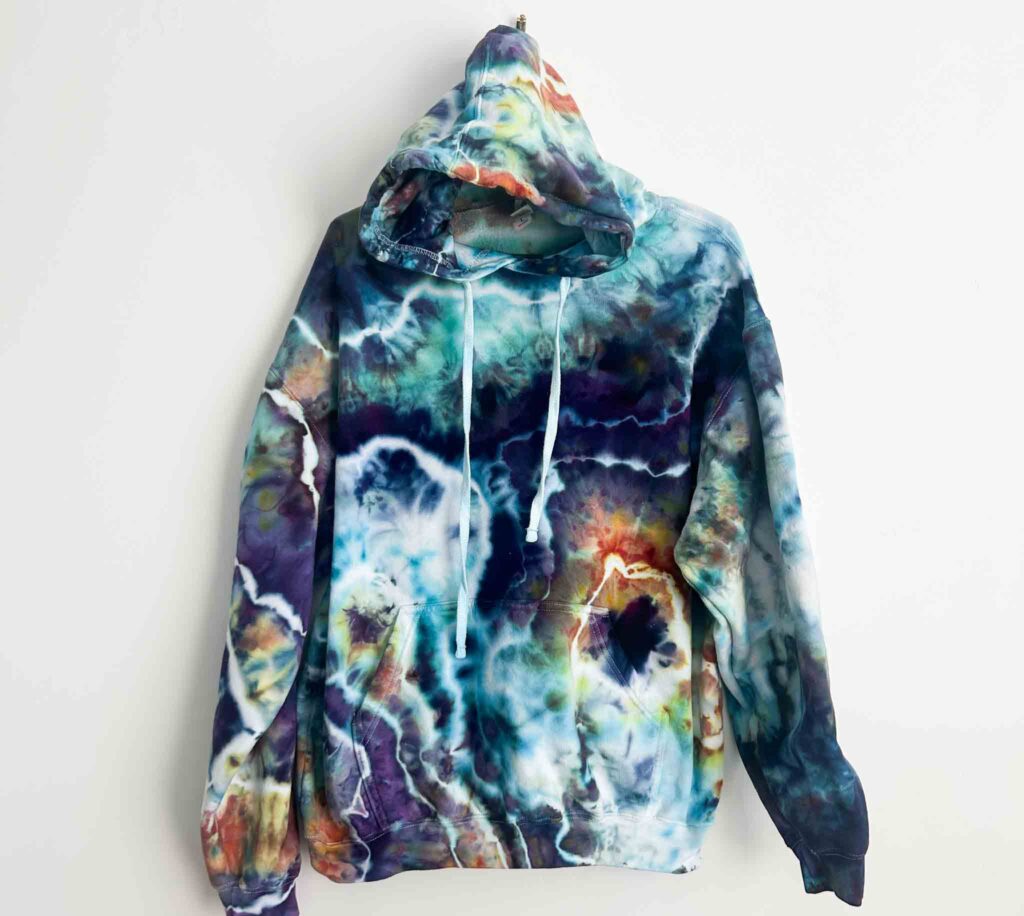 Front view of finished ice dye hoodie with loose geode tie dye pattern in blue, purple, and orange