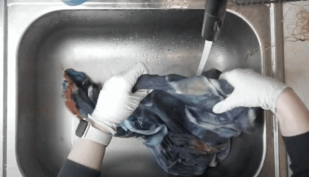 Rinsing tie dye hoodie under running water to remove excess dye