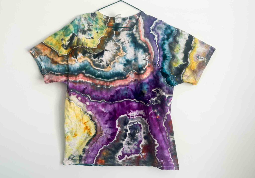 Front view of a handmade geode tie dye shirt with vibrant layers of purple, teal, orange, yellow, and black