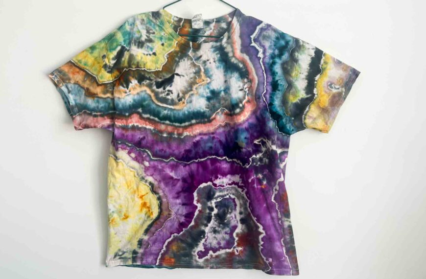 Front view of a handmade geode tie dye shirt with vibrant layers of purple, teal, orange, yellow, and black