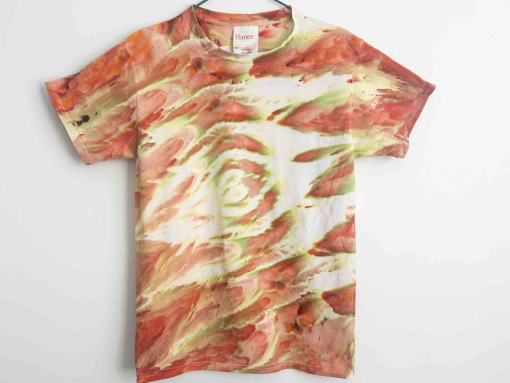 Tie dye t-shirt with orange, red, and yellow gravity dye pattern that looks like swirling autumn leaves.