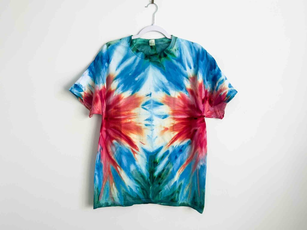 Tie dye t-shirt with vibrant blue and red gravity fold design creating a mirrored burst effect.