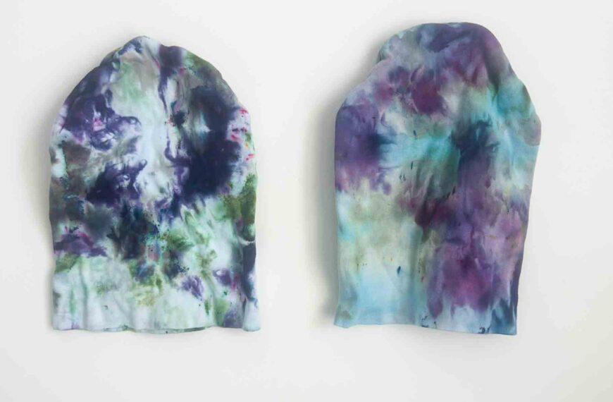 Two tie dye beanies on white background showing color differences between ice dye and hot water methods