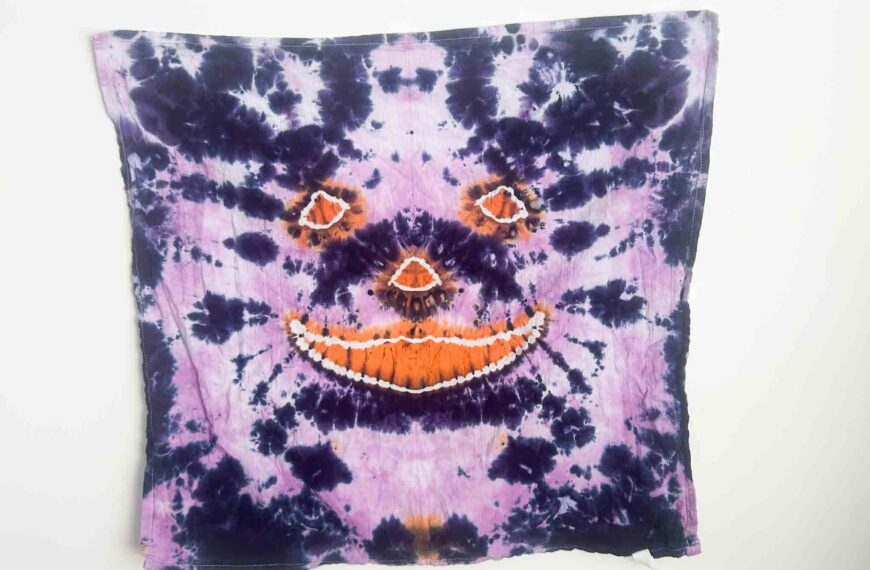 Finished jack-o’-lantern tie dye towel with orange pumpkin face and purple background created using hot water method