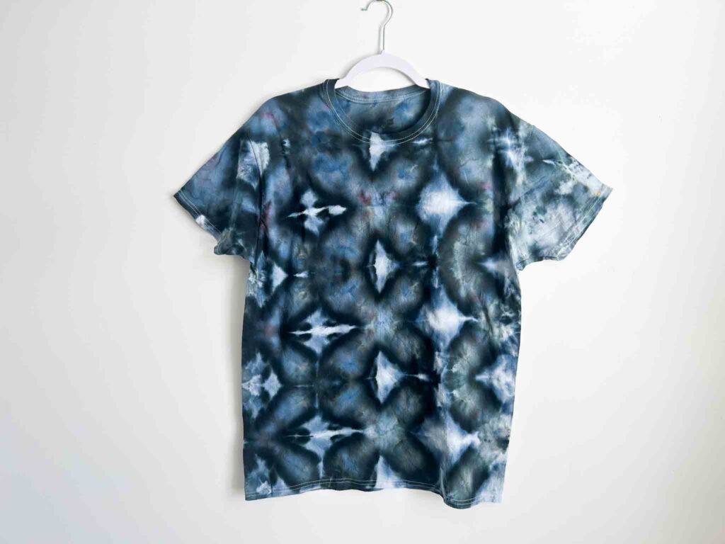 Indigo blue shibori tie dye shirt with geometric diamond patterns created from accordion pleats.