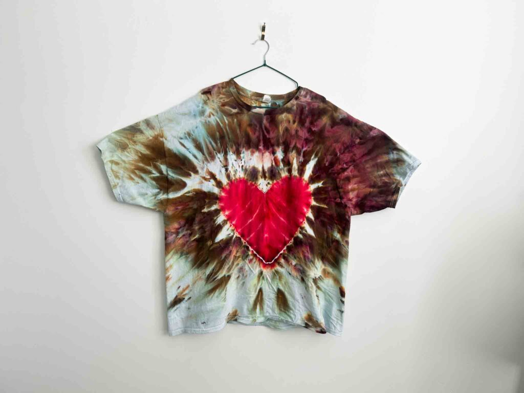 Solid red heart tie dye shirt with gravity dye background in brown and blue tones