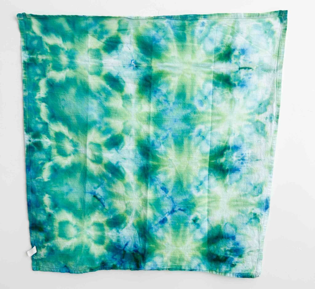 Finished shibori towel dyed with Jacquard ice dye in the Rainforest color, showing teal and green color splits