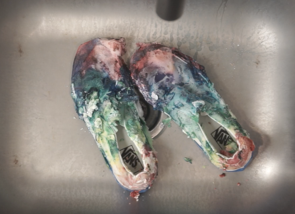 Rinsing shaving cream tie dye canvas shoes in the sink before washing