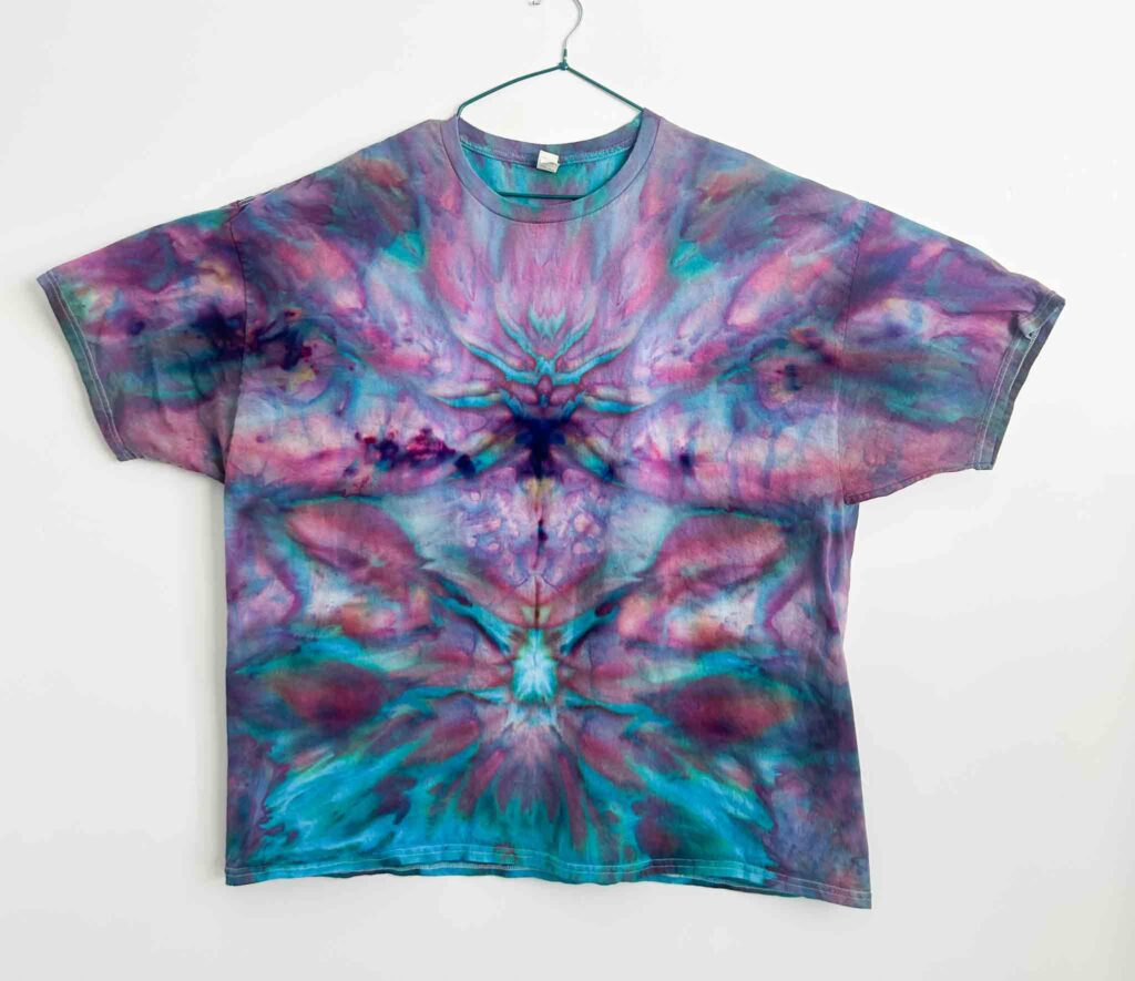 Ice dye deity roll t-shirt with mirrored symmetrical pattern in pink, teal, and purple