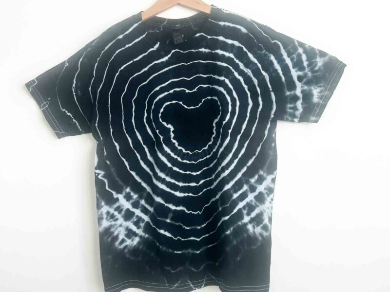 Finished black Mickey Mouse tie dye shirt with white bullseye rings on wooden hanger