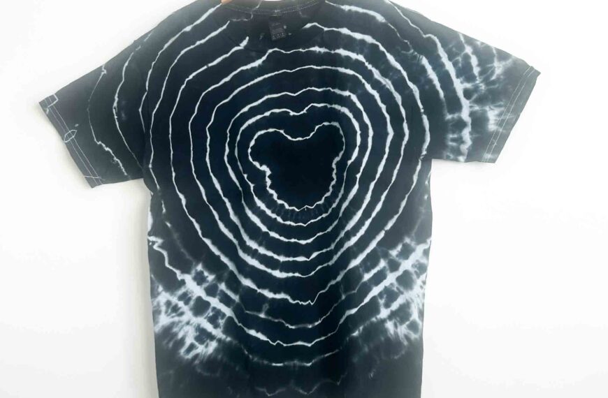 Finished black Mickey Mouse tie dye shirt with white bullseye rings on wooden hanger