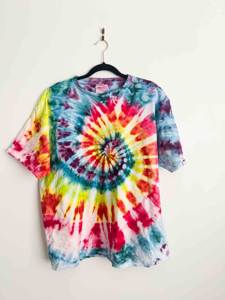 Bright rainbow spiral tie dye t-shirt in red, yellow, teal, purple, and pink on a black hanger