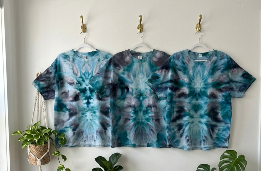 Three white t-shirts tie dyed in matching blue and teal deity roll patterns, displayed side by side for comparison