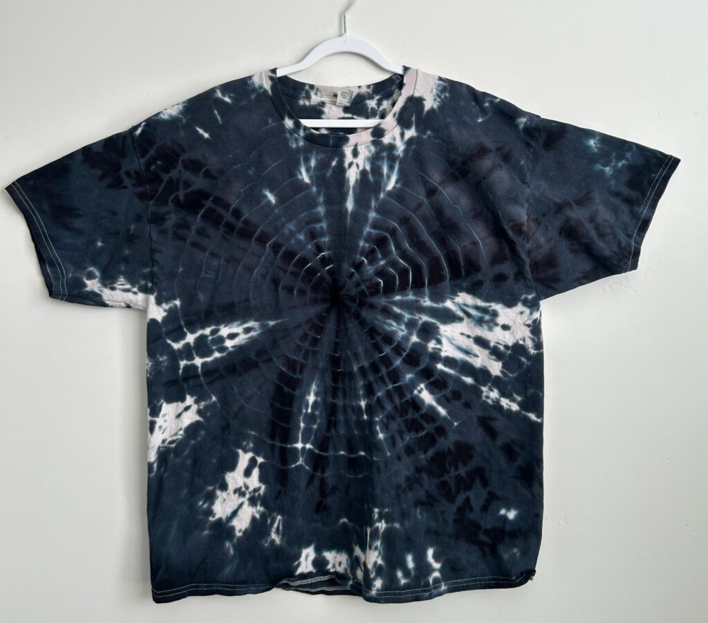 Front of a black bullseye tie dye t-shirt made with liquid fiber reactive dye, showing crisp concentric rings radiating from a center point.