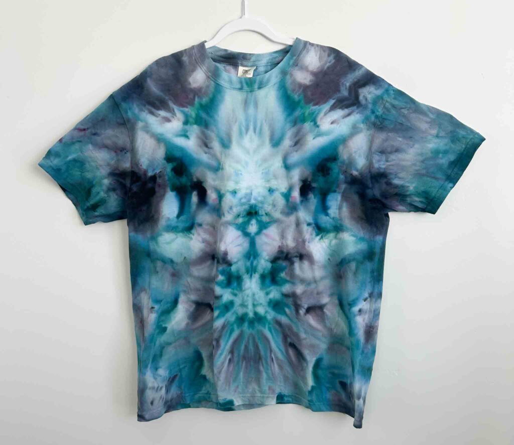 Comfort Colors white t-shirt tie dyed in a deity roll, with cotton thread seams that take the dye