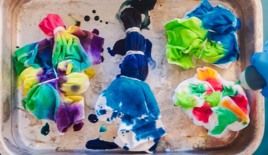 Folded and banded shirts being dyed with the Create Basics 18 bottle tie dye party tub
