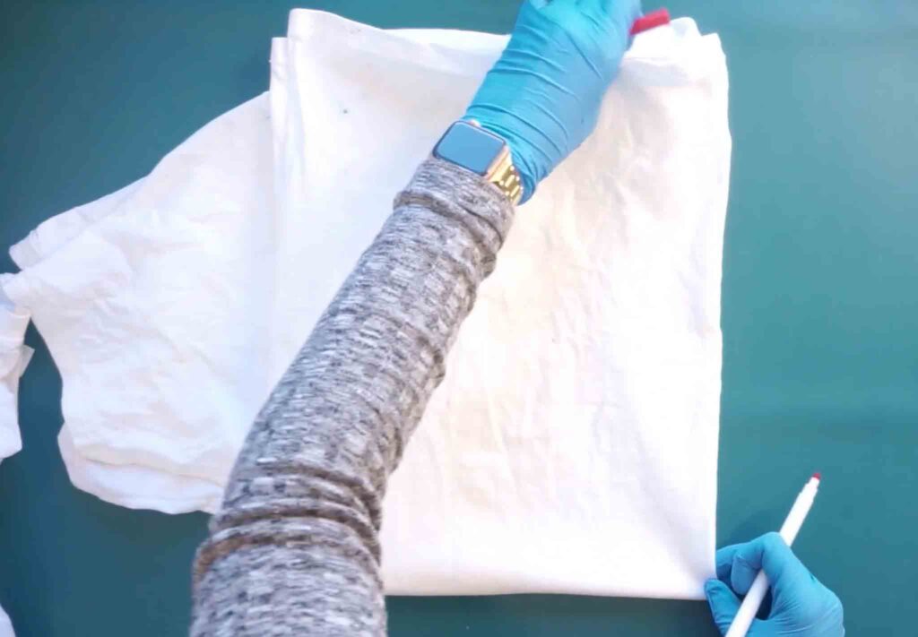 Finding the center of a white cotton shirt at armpit height to start a bullseye tie dye fold