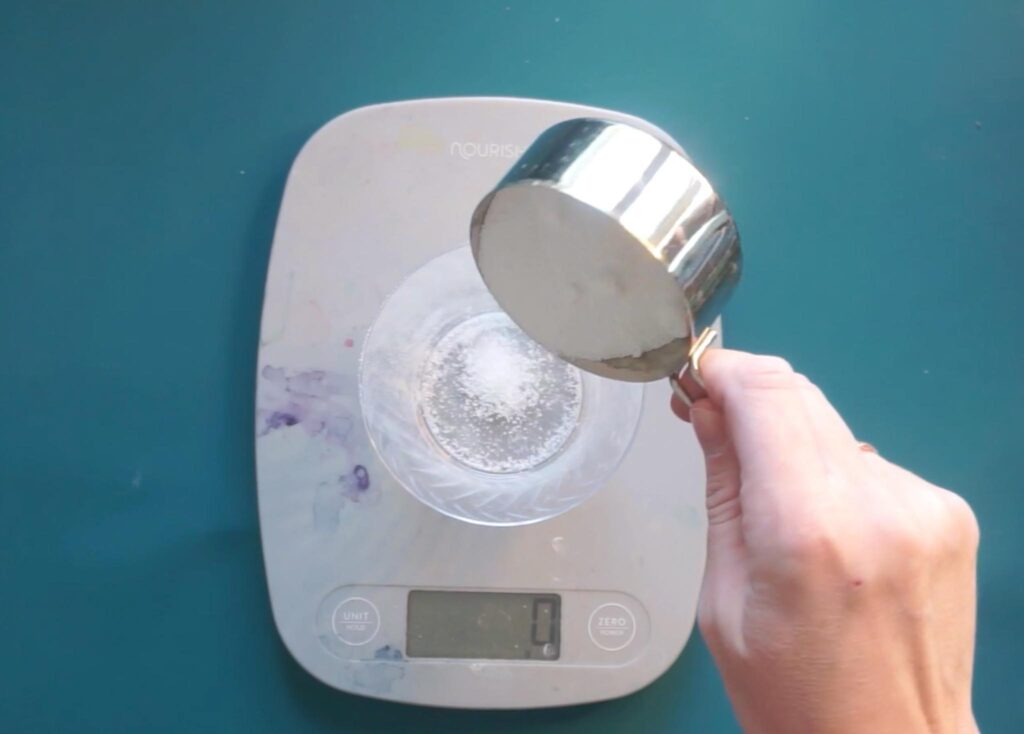Measuring alum powder on a scale for the mordant bath before dyeing with logwood