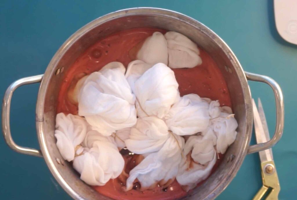 Sinew-tied fabric bundles simmering in a madder root dye pot