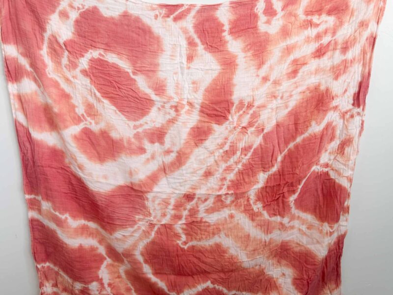 Finished swaddle with a deep red and coral shibori pattern using madder root dye