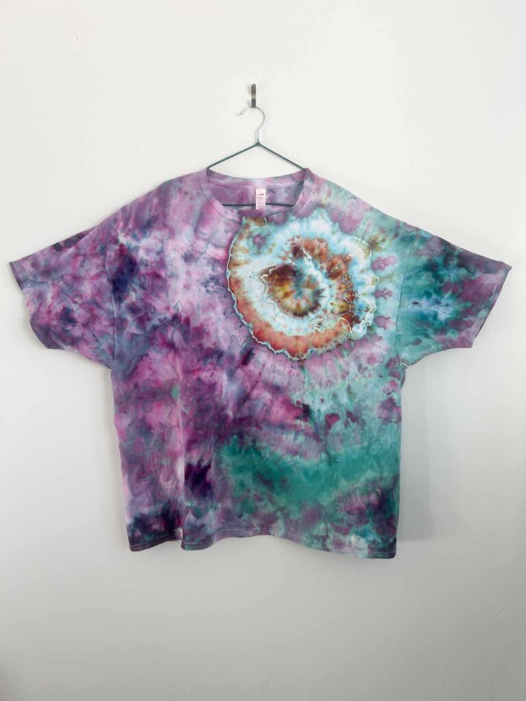 Purple and teal nautilus tie dye t-shirt hanging on a hanger