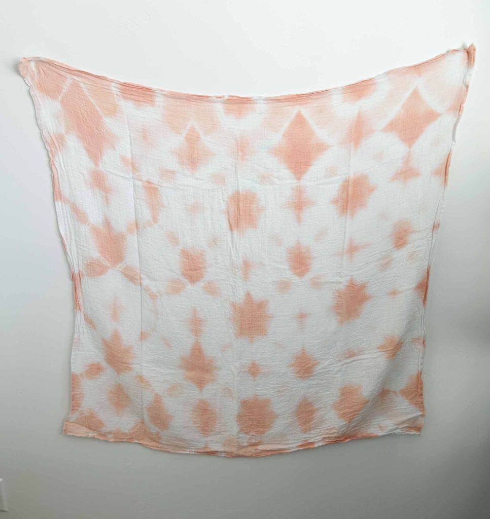 Finished swaddle with a coral diamond shibori pattern from dyeing with madder