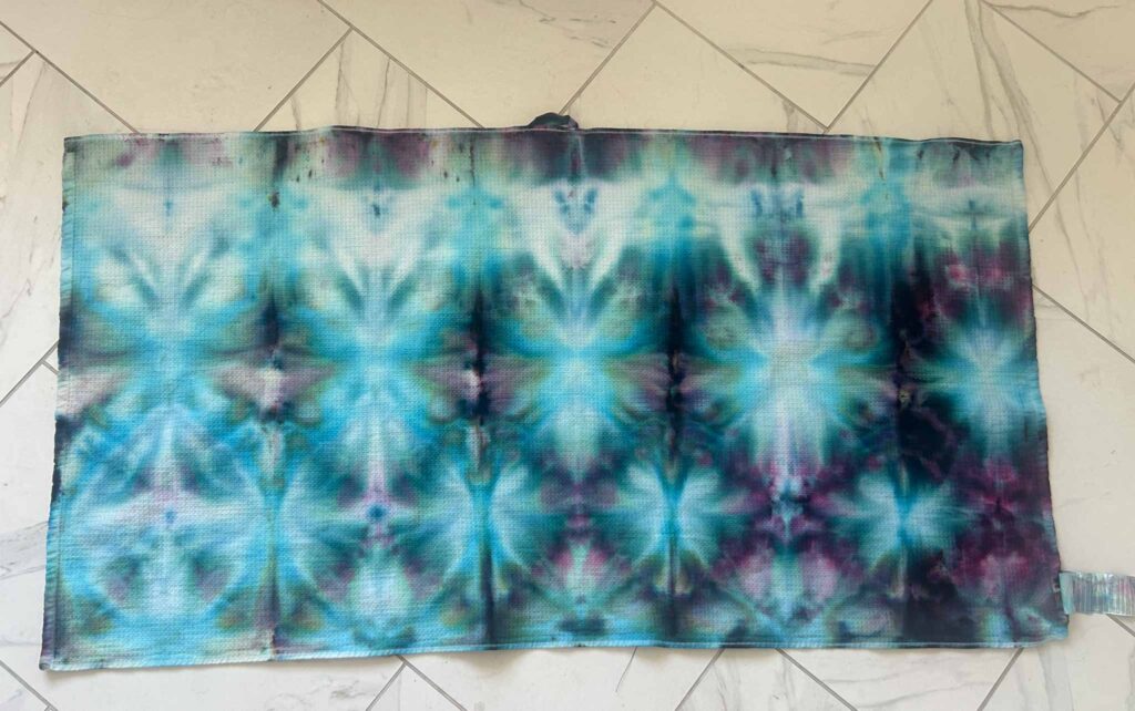 Finished teal, blue, and purple shibori tie dye beach towel laid flat showing the full pattern