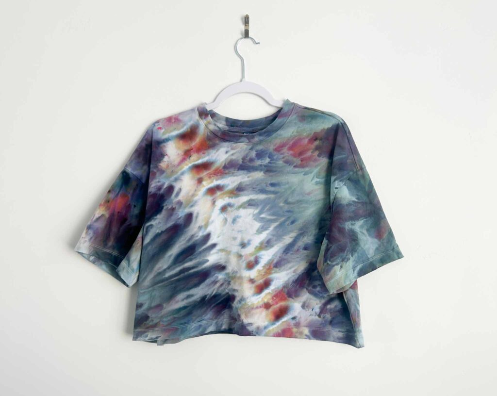 Psychedelic roll tie dye pattern in muted teal, purple, and red on a cropped t-shirt