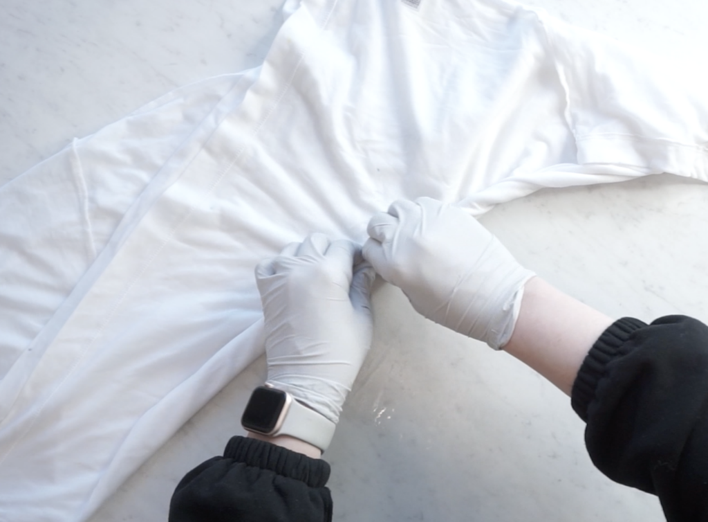 Folding a white t-shirt using the tight center roll technique for a psychedelic roll tie dye