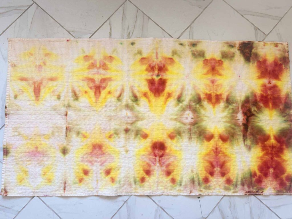 Finished yellow, orange, and red shibori tie dye beach towel laid flat showing the full pattern