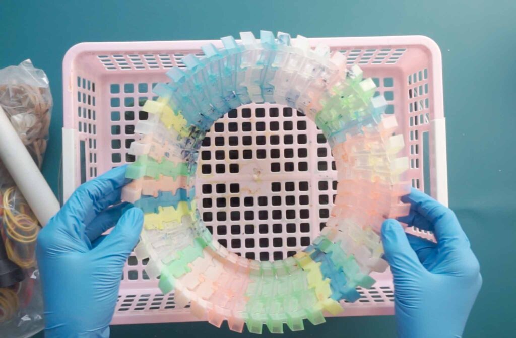 Rubber banded tie dye shirt resting in a perforated basket before dye is applied