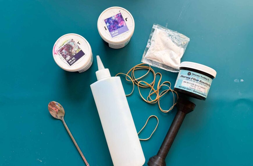 Tie dye supplies flat lay with Dharma fiber reactive dye, soda ash, squeeze bottle, rubber bands, and sinew puller
