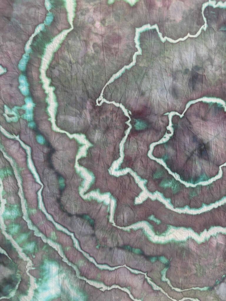 Close-up of Aurora ice dye showing dusty mauve purple with bright teal edges along the sinew lines