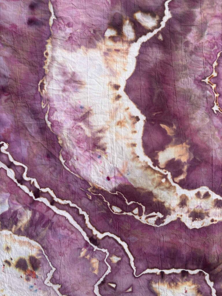 Close-up of Chocolate Cherries ice dye with dark chocolate brown speckles and tan halos on plum fabric