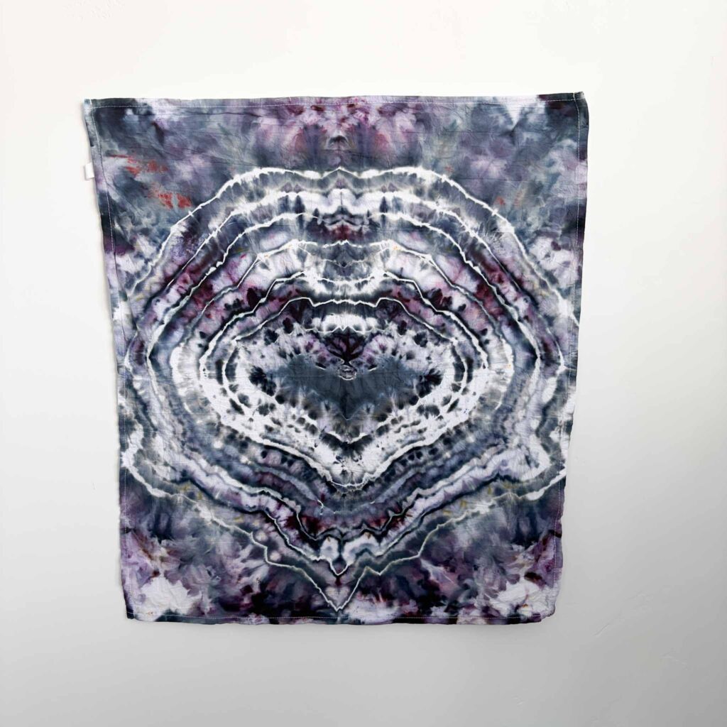 Bat shape tie dye towel in dark purple and charcoal with white bullseye rings around a black bat
